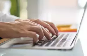 Hände, die auf einer Laptop-Tastatur tippen