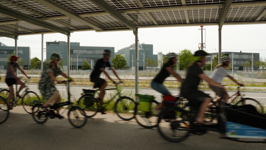 Gruppe von radfahrenden Personen unter Solardach