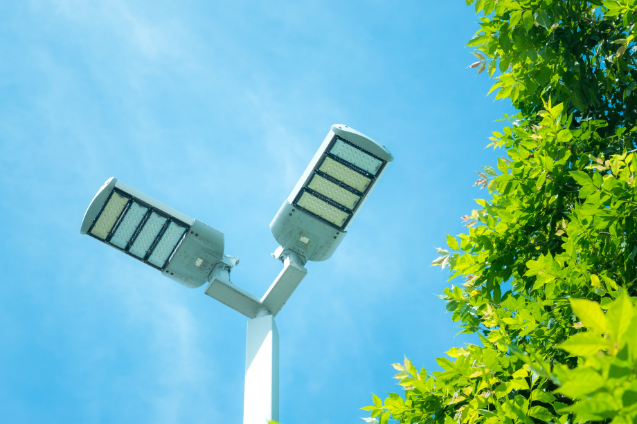 LED-Außenbeleuchtung von unten aufgenommen. Rechts wird das Bild durch die Blätter eines Baumes begrenzt. 