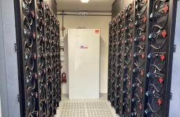 Ein Raum mit zwei Reihen von elektrischen Speichern an den Wänden und einem weißen Schaltkasten in der Mitte.