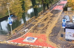 Luftbild der Einfahrt zur Fahrradstraße, am Rand ein Kanal und Herbstbäume, sowie Autos und Schilder