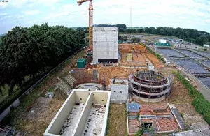 Blick von oben auf eine Kläranlage, viele Becken, Rohre und ein Gebäude