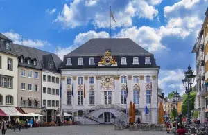 Ein Rathaus im Stil des Barock, davor ein großzügiger Marktplatz und Fahnen.