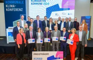 Die Teams der sechs ausgezeichneten Kommunen des Wettbewerbs „Klimaaktive Kommune 2024“ gemeinsam mit Gratulanten auf der Bühne der Kommunalen Klimakonferenz in Berlin